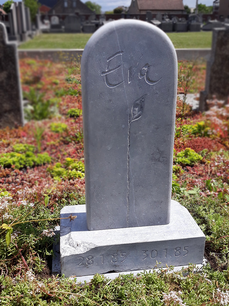 Kleine grafsteen met gekapte letters en blad